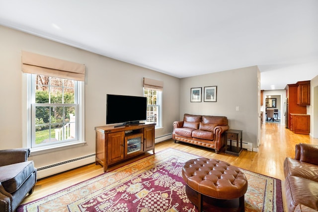 living room with light wood-type flooring, a baseboard radiator, and baseboards