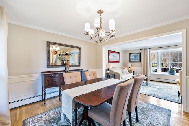 dining room featuring a wainscoted wall, a baseboard radiator, crown molding, and wood finished floors