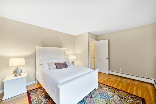 bedroom with light wood-type flooring, baseboards, and a baseboard radiator