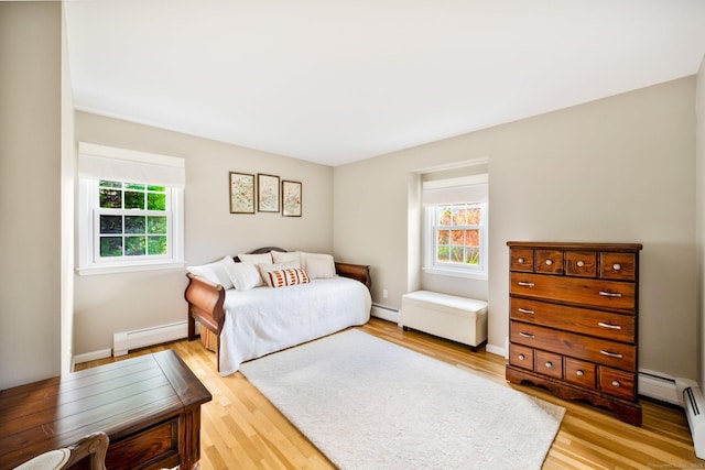 bedroom with light wood-type flooring, a baseboard radiator, baseboards, and baseboard heating