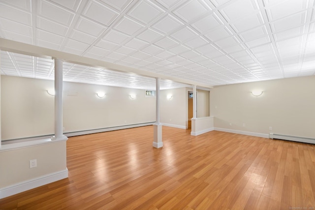 finished basement with a baseboard heating unit, light wood-type flooring, baseboard heating, and baseboards