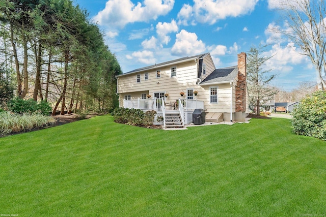 rear view of property featuring a chimney, a deck, and a yard