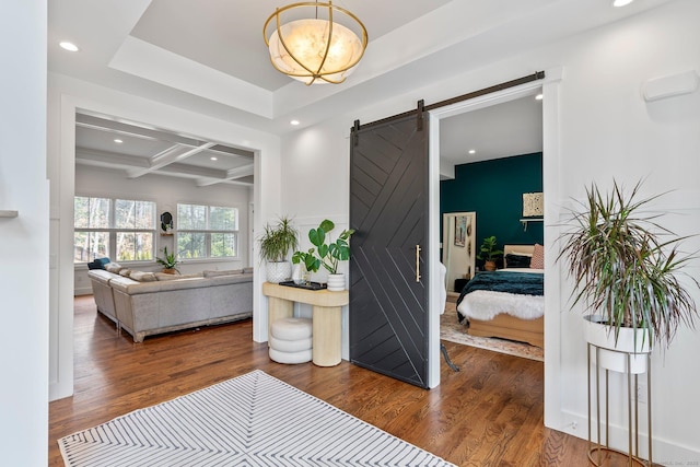 hall with a barn door, coffered ceiling, beamed ceiling, and wood finished floors