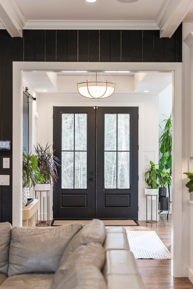 entryway featuring wood finished floors, a barn door, plenty of natural light, and ornamental molding