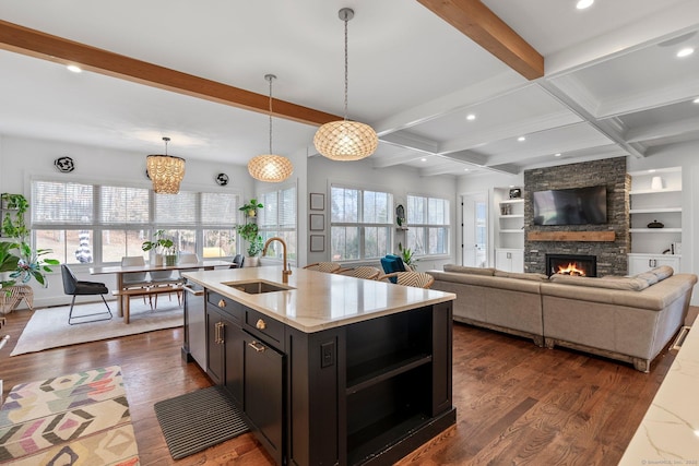 kitchen with beamed ceiling, dark wood-style flooring, stainless steel dishwasher, and a sink