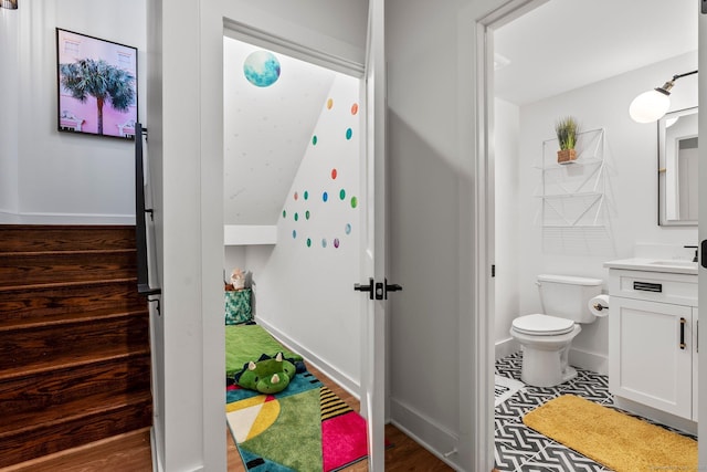 half bath with toilet, vanity, and baseboards