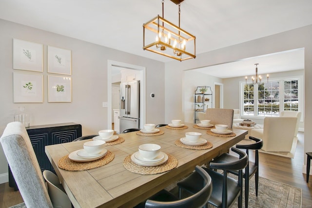 dining area with dark wood-style flooring and an inviting chandelier