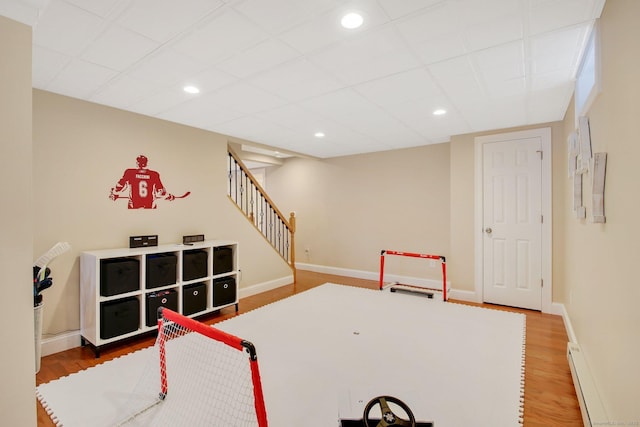 recreation room with a baseboard radiator, baseboards, wood finished floors, and recessed lighting