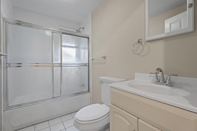 bathroom featuring tile patterned flooring, vanity, toilet, and bath / shower combo with glass door