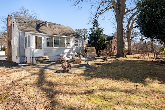 view of front of home featuring entry steps, a front lawn, a chimney, and a patio area