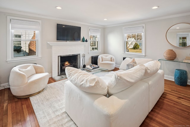 living area featuring a brick fireplace, plenty of natural light, and crown molding