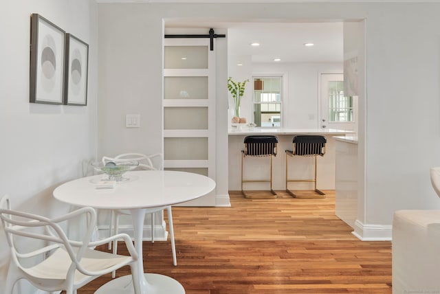 dining space with light wood finished floors, a barn door, and recessed lighting