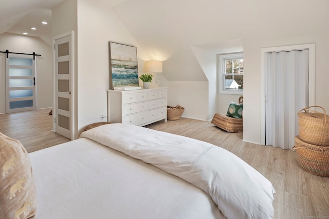 bedroom with lofted ceiling, wood finished floors, recessed lighting, and a barn door