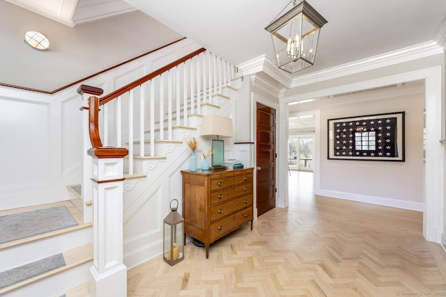 stairs featuring crown molding, an inviting chandelier, and a decorative wall