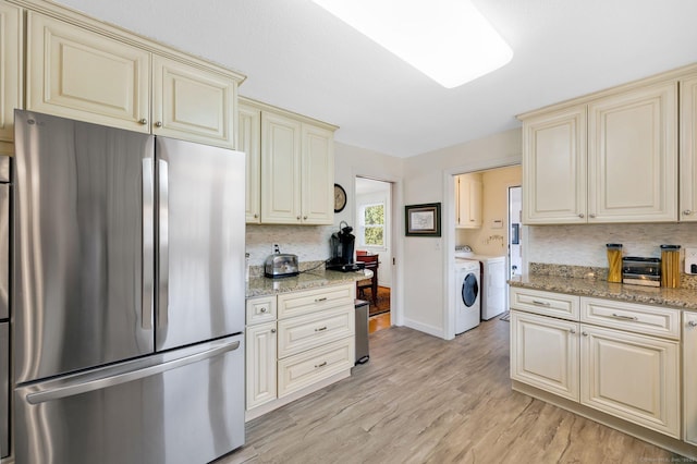 kitchen featuring independent washer and dryer, tasteful backsplash, cream cabinets, freestanding refrigerator, and light wood-style floors