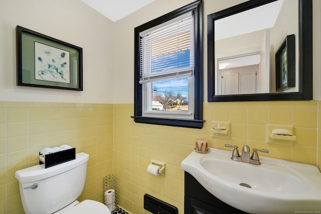 half bath with vanity, toilet, and tile walls