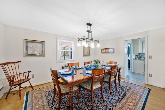 dining area featuring baseboards, a notable chandelier, light wood-style flooring, and crown molding