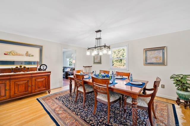 dining space with light wood finished floors, baseboards, and ornamental molding