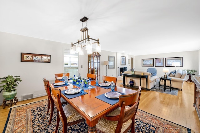 dining space featuring visible vents, a large fireplace, baseboards, and light wood-style flooring