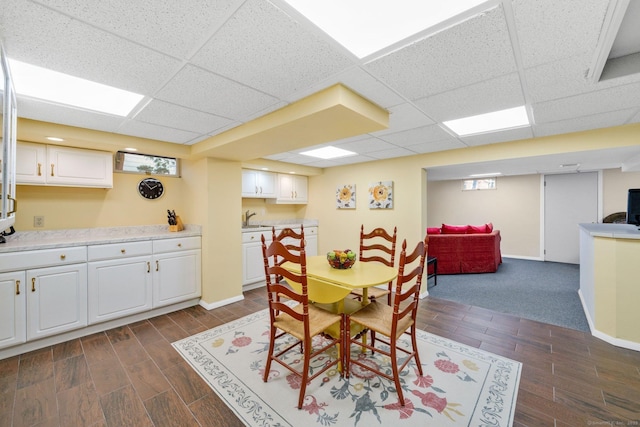 dining space featuring wood finish floors, a paneled ceiling, and baseboards