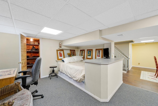 carpeted bedroom featuring a paneled ceiling and baseboards