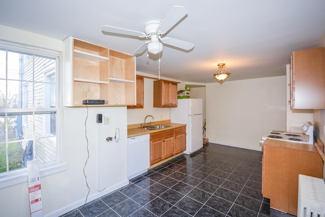 kitchen featuring light countertops, a sink, ceiling fan, white appliances, and baseboards