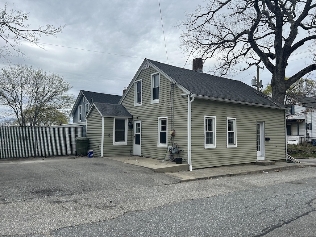view of front facade featuring a shingled roof and a chimney