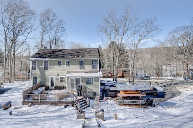 snow covered back of property featuring a hot tub and a wooden deck