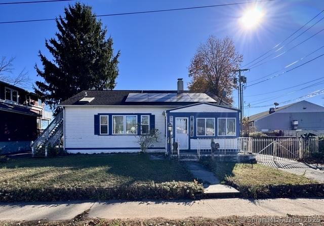 view of front of house with a front lawn and solar panels