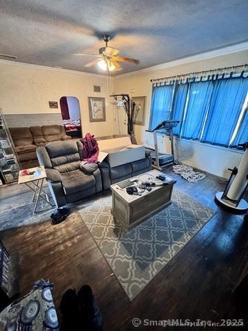 living room featuring a textured ceiling, crown molding, ceiling fan, and wood-type flooring