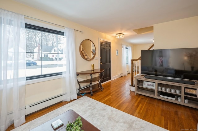 living room featuring a baseboard radiator, baseboards, and wood finished floors