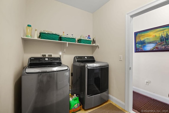 clothes washing area featuring laundry area, washing machine and clothes dryer, and baseboards