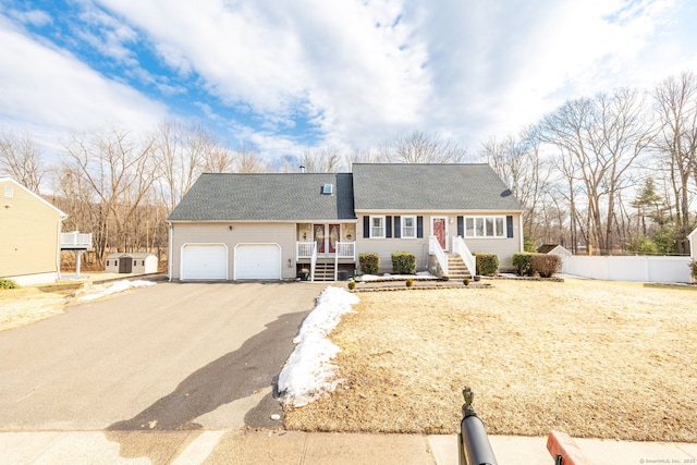 view of front of home featuring aphalt driveway, a porch, a garage, fence, and roof with shingles