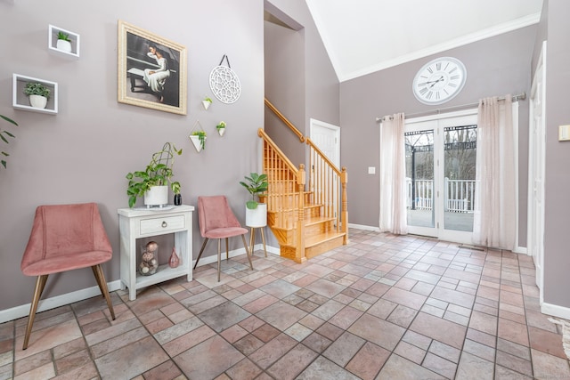 entryway featuring baseboards, ornamental molding, stone finish flooring, stairs, and high vaulted ceiling