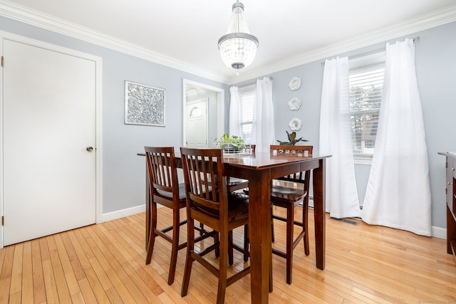 dining area with light wood-style floors, plenty of natural light, and ornamental molding