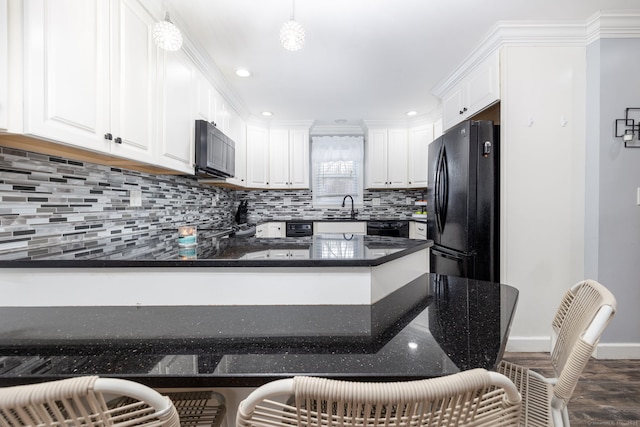 kitchen featuring tasteful backsplash, a peninsula, black appliances, white cabinetry, and a sink