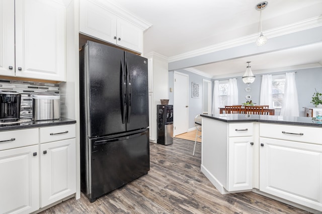 kitchen with dark countertops, white cabinetry, ornamental molding, and freestanding refrigerator