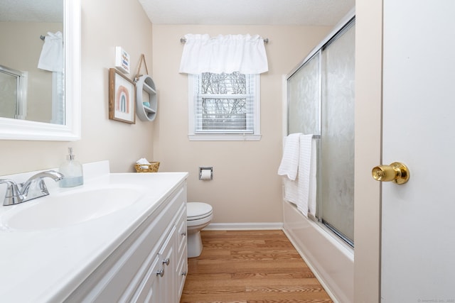 bathroom featuring baseboards, toilet, enclosed tub / shower combo, wood finished floors, and vanity