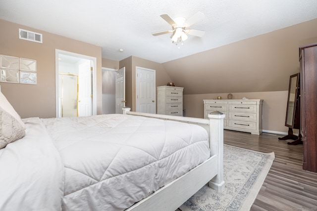 bedroom featuring baseboards, visible vents, lofted ceiling, dark wood-style flooring, and a textured ceiling