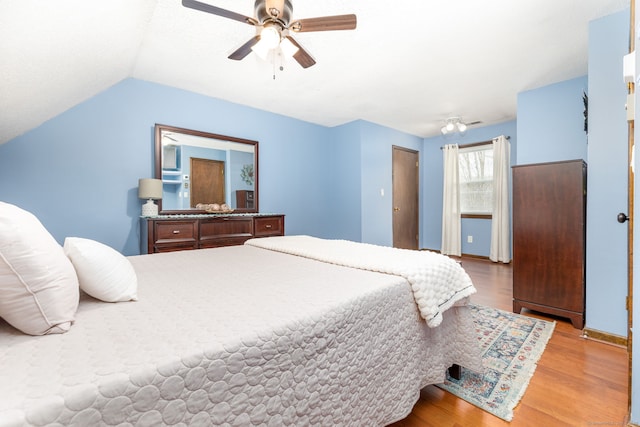 bedroom featuring lofted ceiling, baseboards, light wood-style flooring, and a ceiling fan