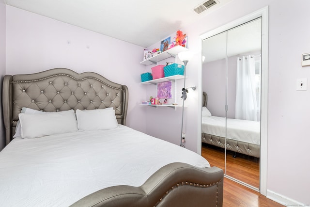 bedroom featuring a closet, visible vents, baseboards, and wood finished floors