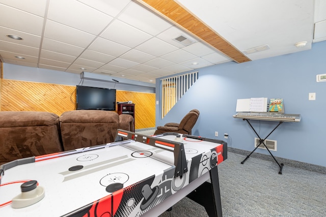 game room with carpet, visible vents, wood walls, and a paneled ceiling