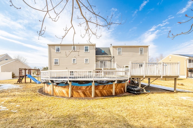 rear view of property with a playground, a yard, and a deck