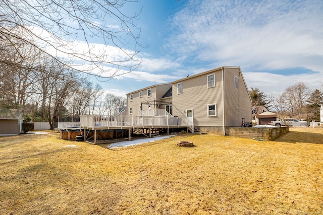 back of property featuring a fire pit, a deck, and a yard