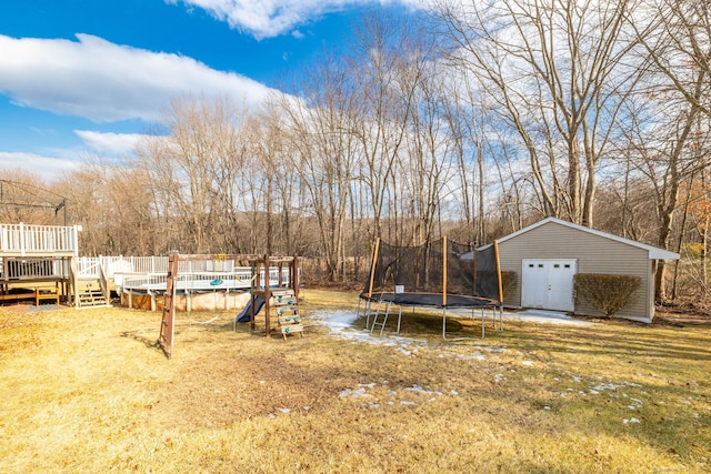 view of yard featuring a trampoline, an outdoor structure, and a wooden deck