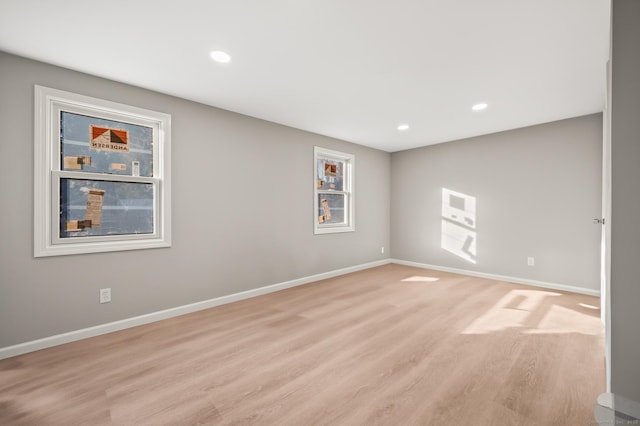 empty room featuring light wood-type flooring, baseboards, and recessed lighting