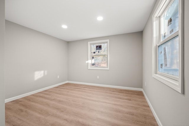 empty room with light wood-type flooring, baseboards, and recessed lighting