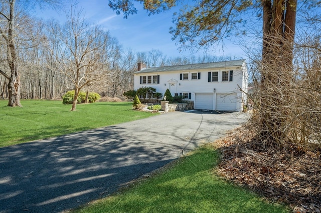 bi-level home with driveway, an attached garage, a chimney, and a front yard