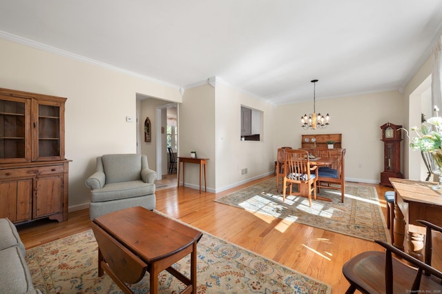 living area with light wood-type flooring, crown molding, and a notable chandelier