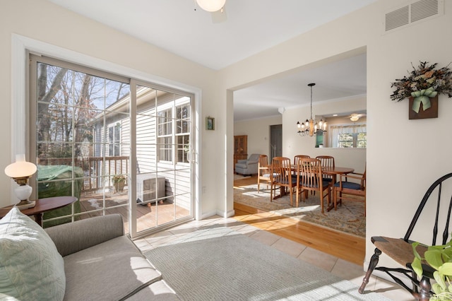 doorway to outside featuring light tile patterned floors, crown molding, visible vents, and a notable chandelier